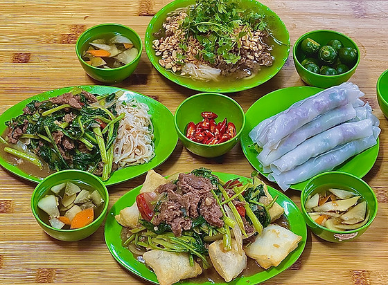 A traditional Vietnamese meal spread on a wooden table, featuring dishes such as pho, fresh spring rolls, and small bowls of soup and condiments.