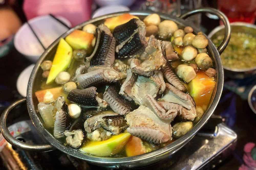 A traditional soup or stew from Vietnam with various ingredients, including what appears to be chicken feet and assorted vegetables.