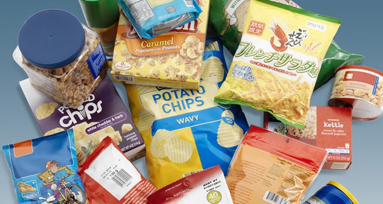 An assortment of snack packages including chips, popcorn, cookies, and pho from Vietnam on a blue background.