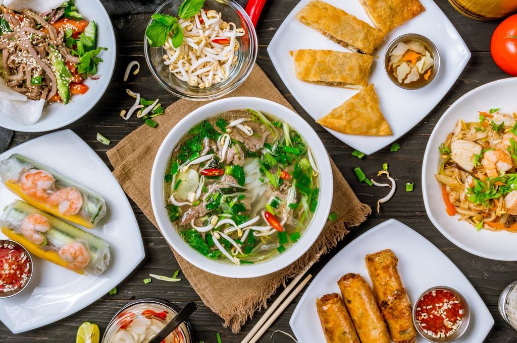 Assorted traditional Vietnamese dishes, including pho, displayed on a wooden table.