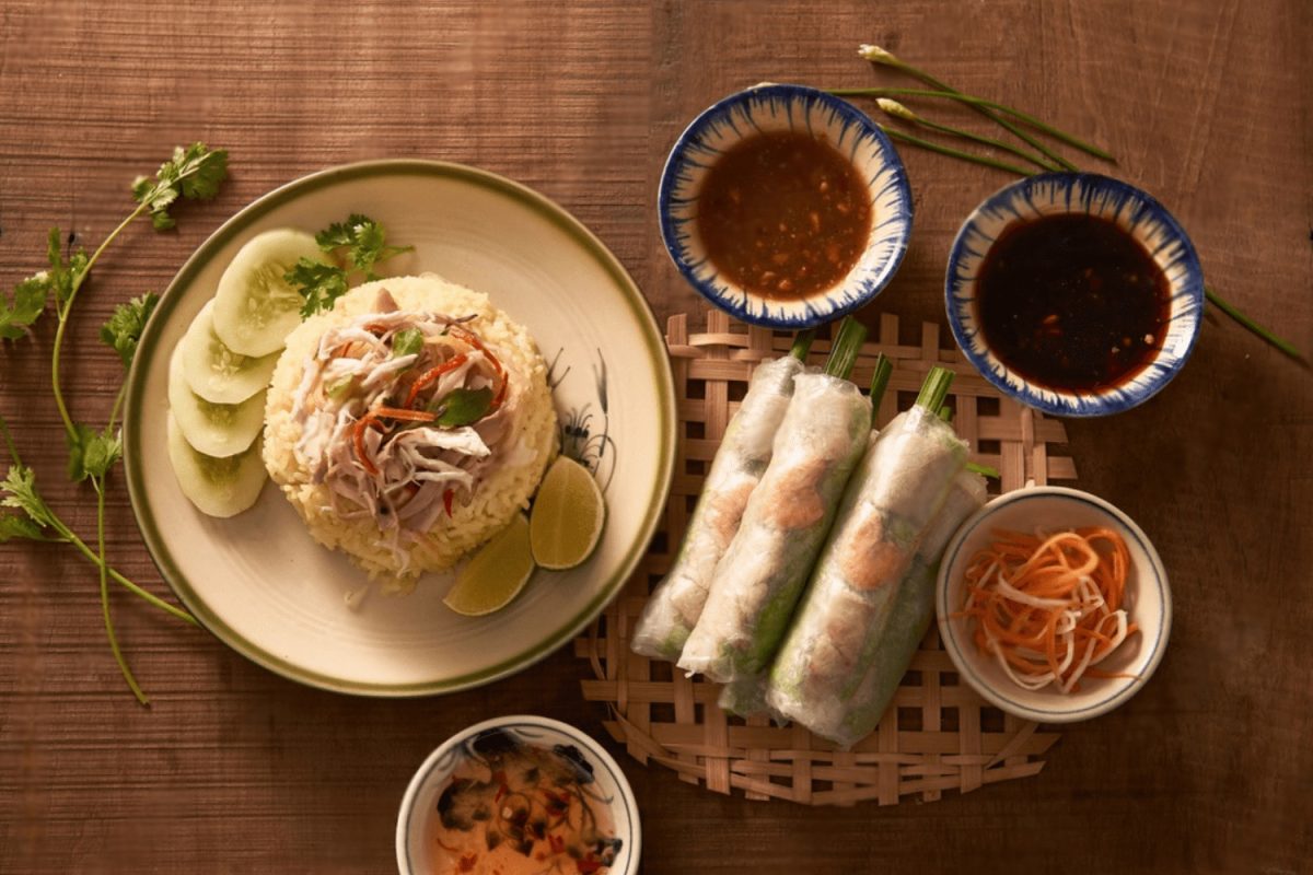 A Vietnamese meal featuring pho, fried rice, and fresh spring rolls with side dishes and dipping sauces.