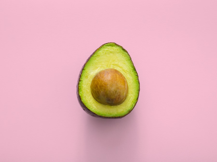 Half of an avocado with pit on a pink background reminiscent of Vietnam.