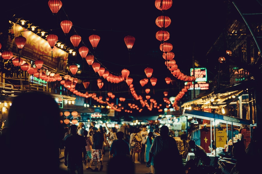 Night market in Vietnam bustling with activity under a canopy of red lanterns.