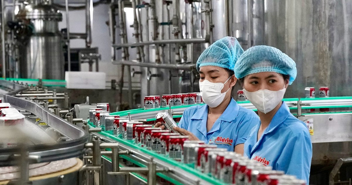 Workers monitoring a pho beverage production line at a Vietnam factory.