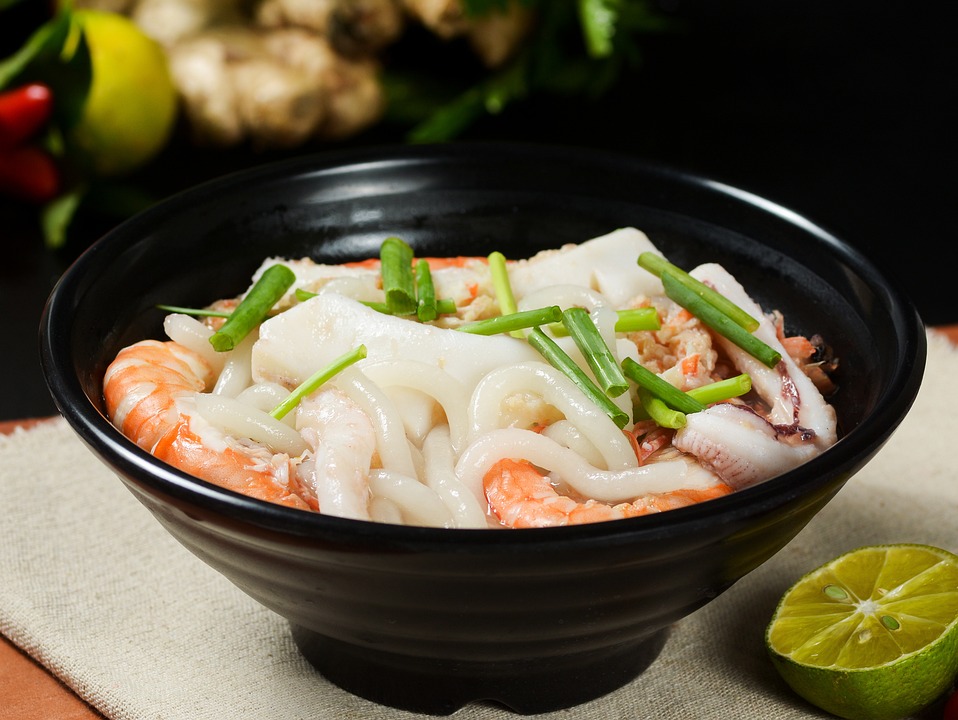 A bowl of pho with shrimp and garnished with green onions, a popular dish from Vietnam.